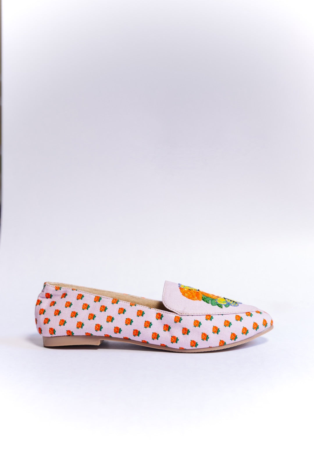 A single light pink loafer shoe with embroidered orange and yellow flowers, green leaves, and small orange floral motifs along the side, shown on a white background.